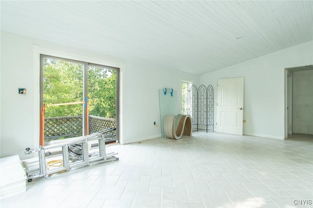 empty room with light tile patterned floors and vaulted ceiling