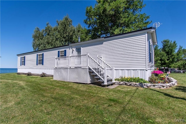 rear view of house featuring a lawn and a deck