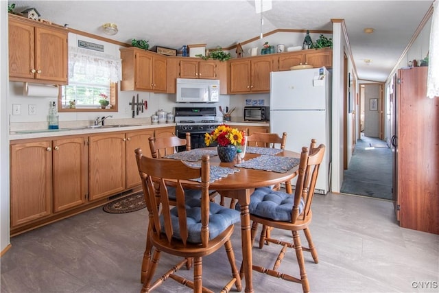 kitchen with light countertops, vaulted ceiling, a sink, white appliances, and brown cabinetry