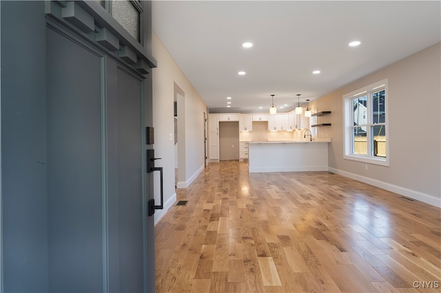 unfurnished living room with light hardwood / wood-style flooring and sink