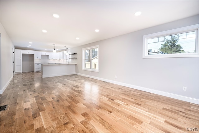 unfurnished living room with light wood-type flooring and sink