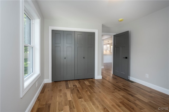 unfurnished bedroom with a closet, multiple windows, and hardwood / wood-style flooring