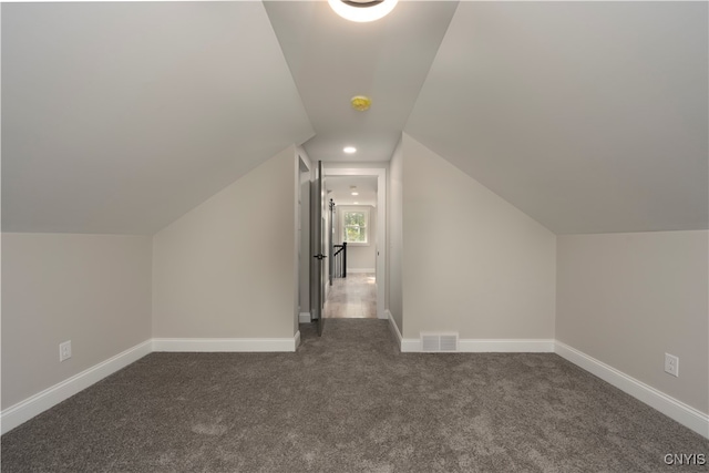 bonus room with vaulted ceiling and dark colored carpet