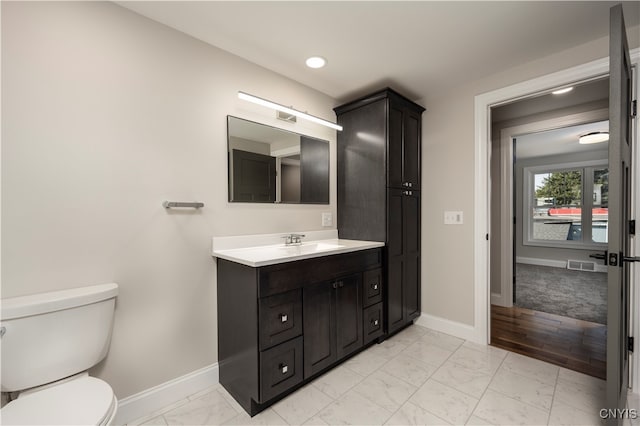 bathroom with wood-type flooring, vanity, and toilet