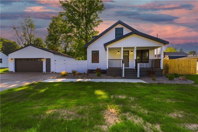 view of front of home with a garage, a lawn, covered porch, and an outbuilding