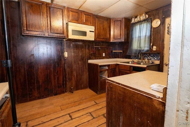 kitchen featuring a drop ceiling, wood walls, sink, and light hardwood / wood-style floors