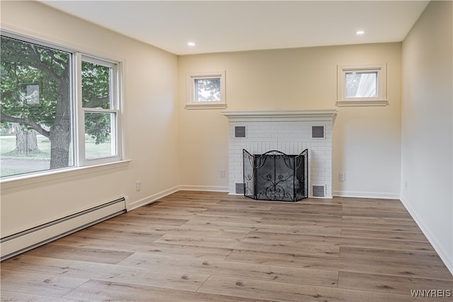 unfurnished living room with a baseboard radiator, light wood-type flooring, and a fireplace