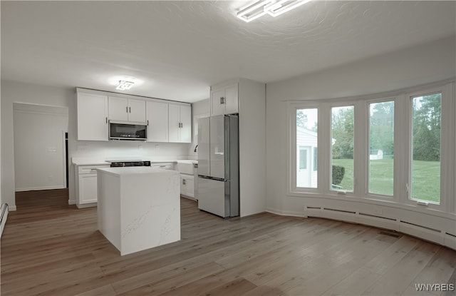 kitchen with refrigerator, a kitchen island, light hardwood / wood-style floors, and white cabinetry