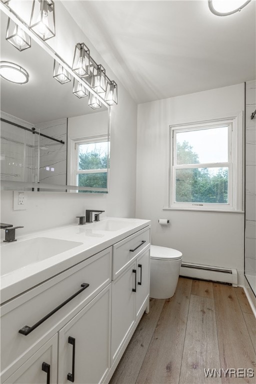 bathroom featuring a baseboard heating unit, walk in shower, vanity, and toilet