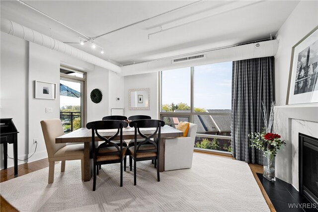 dining space featuring a high end fireplace, track lighting, and hardwood / wood-style flooring