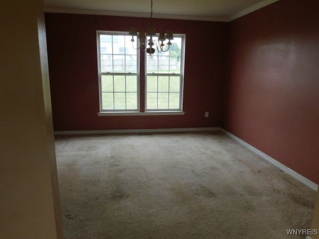 carpeted spare room featuring crown molding and an inviting chandelier