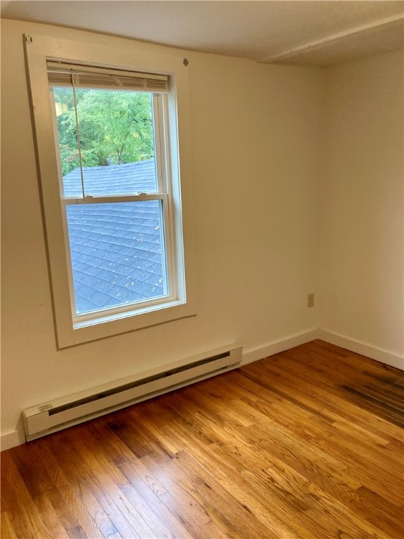 empty room with a baseboard heating unit and light hardwood / wood-style floors