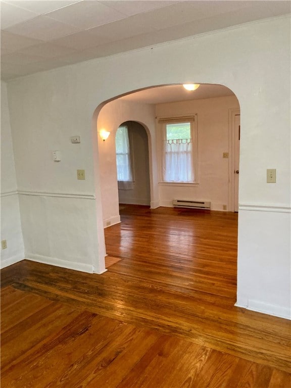 empty room featuring baseboard heating and hardwood / wood-style floors