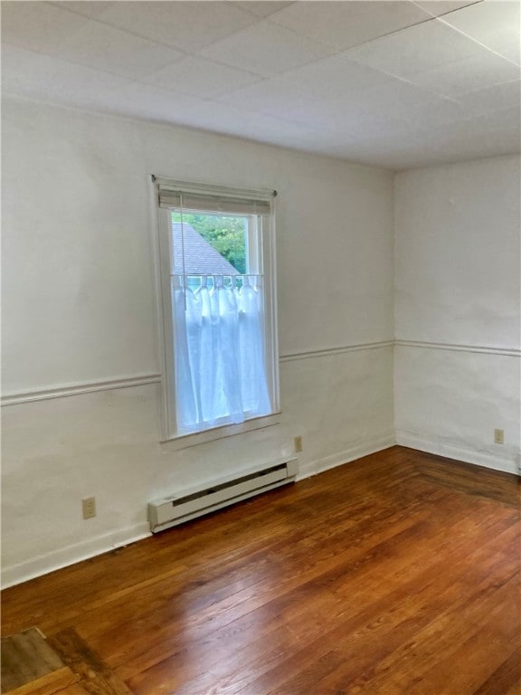 unfurnished room featuring wood-type flooring and baseboard heating