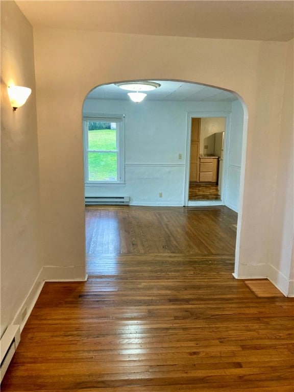 spare room with a baseboard radiator and dark hardwood / wood-style floors