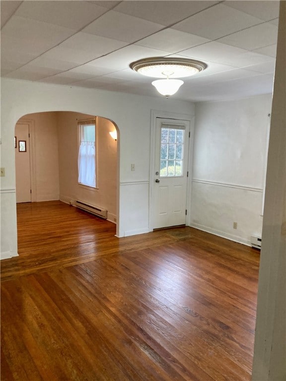 unfurnished room with a baseboard radiator, wood-type flooring, and a drop ceiling