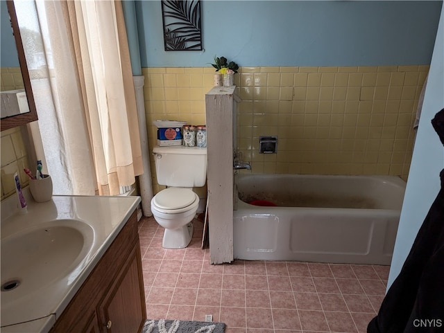 bathroom featuring tile walls, vanity, a washtub, toilet, and tile patterned floors