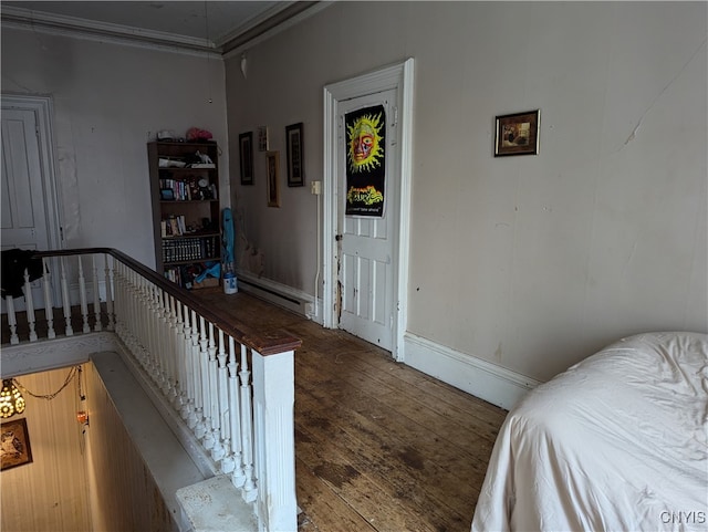 bedroom with a baseboard heating unit, dark hardwood / wood-style floors, and crown molding