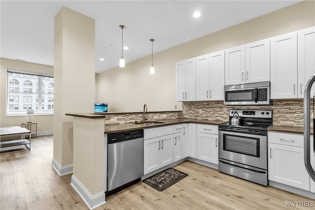 kitchen featuring white cabinetry, pendant lighting, stainless steel appliances, light hardwood / wood-style flooring, and sink