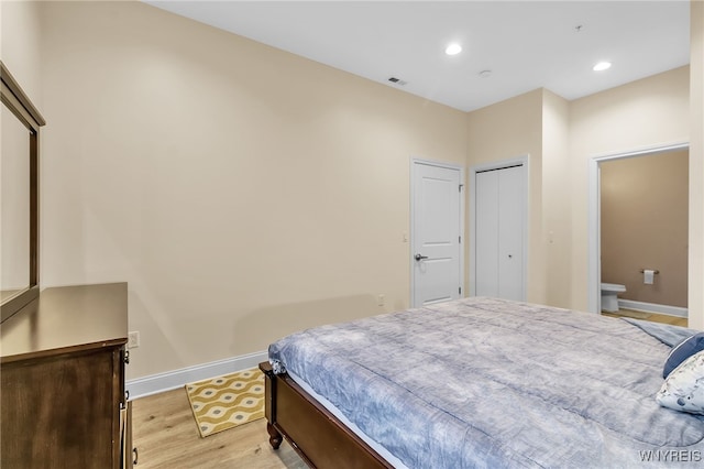 bedroom featuring connected bathroom and light hardwood / wood-style floors