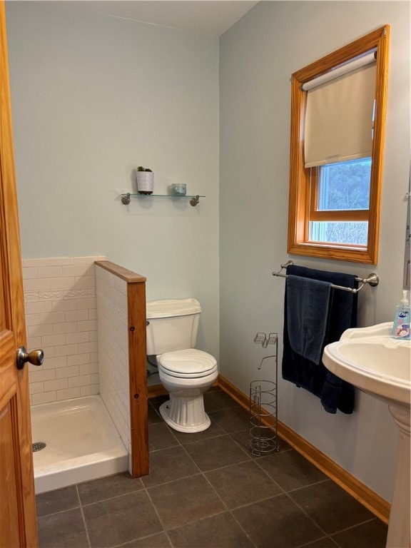 bathroom featuring a tile shower, tile patterned flooring, and toilet