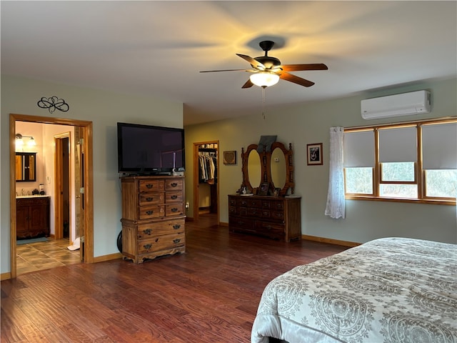 bedroom with ceiling fan, a wall mounted AC, a walk in closet, and hardwood / wood-style flooring