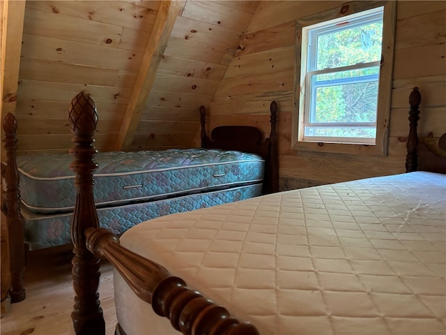 bedroom with hardwood / wood-style flooring, wooden walls, and lofted ceiling with beams