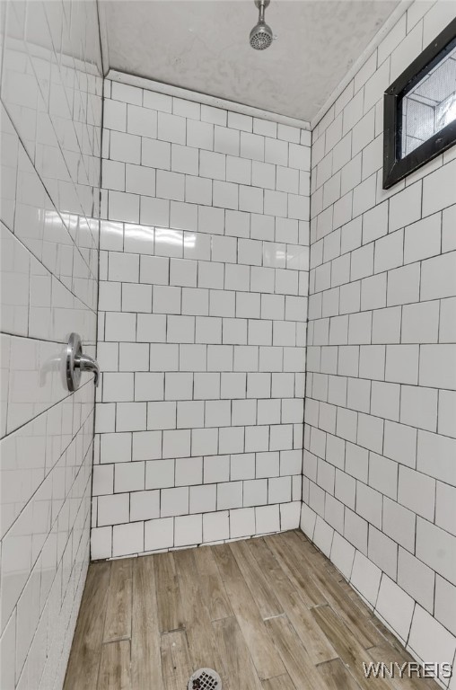 bathroom with a tile shower and hardwood / wood-style floors