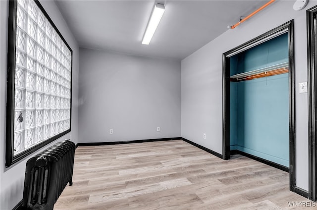 unfurnished bedroom featuring radiator, light wood-type flooring, and a closet