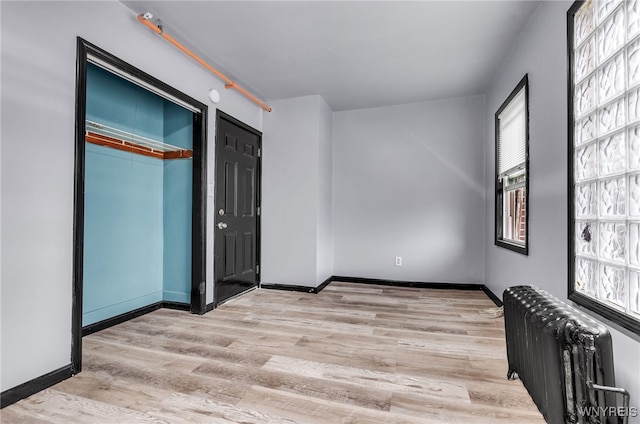 unfurnished bedroom featuring a closet, radiator heating unit, and light hardwood / wood-style flooring