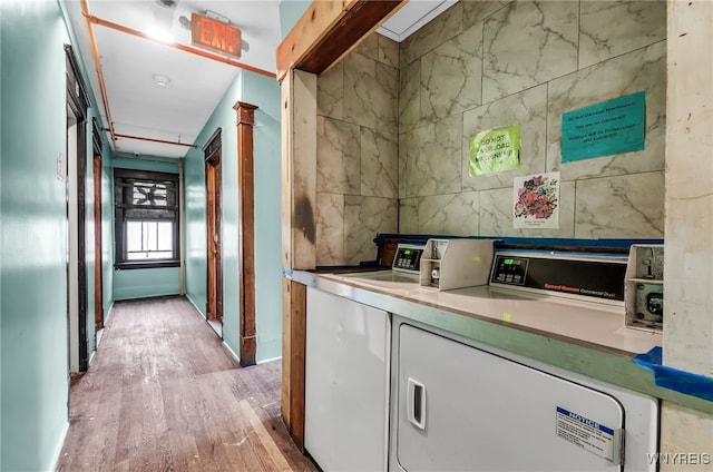 interior space featuring tile walls, light hardwood / wood-style floors, and washing machine and clothes dryer