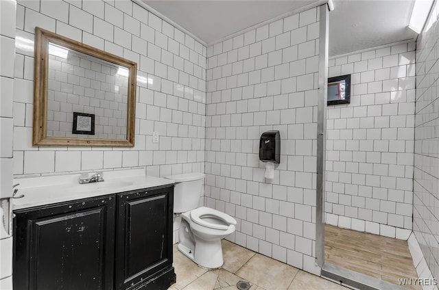 bathroom with tile walls, vanity, toilet, and tile patterned floors