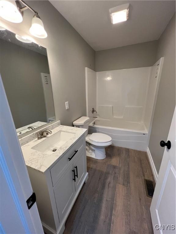 full bathroom featuring vanity, hardwood / wood-style flooring, toilet, and shower / bathtub combination