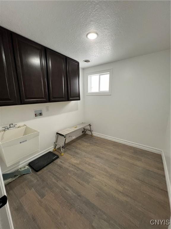 washroom featuring sink, cabinets, washer hookup, dark hardwood / wood-style floors, and a textured ceiling