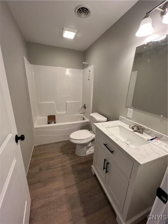 full bathroom with hardwood / wood-style floors, vanity, toilet, and washtub / shower combination