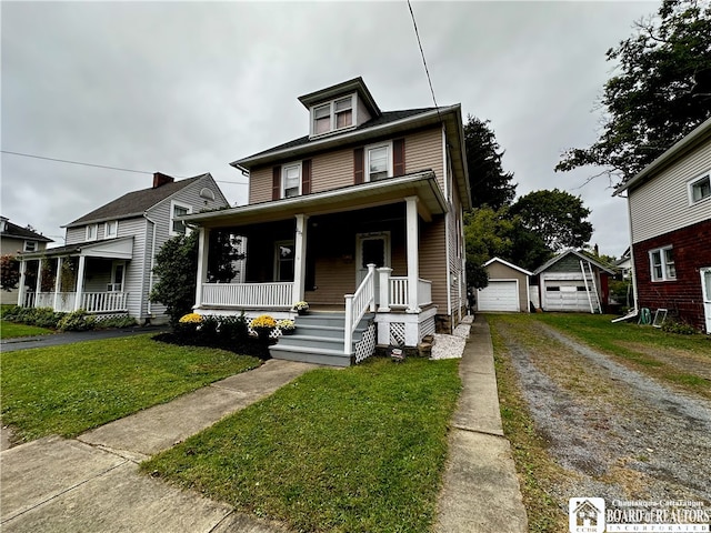 traditional style home featuring driveway, a detached garage, an outbuilding, covered porch, and a front yard