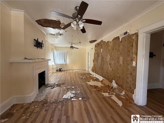 unfurnished living room featuring ornamental molding, a fireplace, wood finished floors, and visible vents