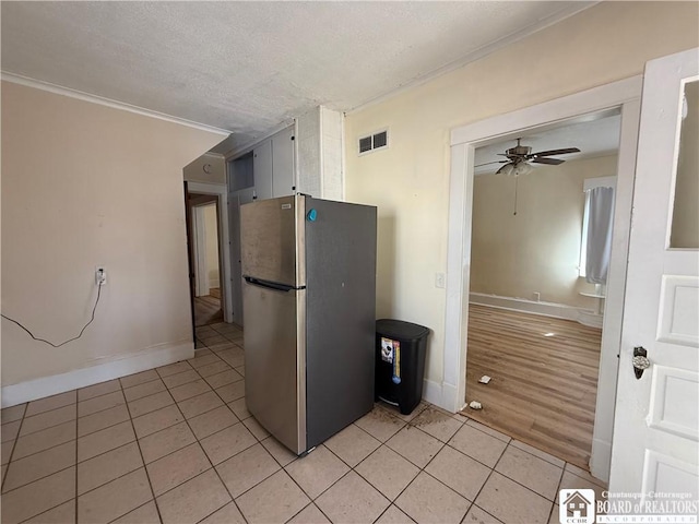 kitchen featuring light tile patterned floors, ceiling fan, visible vents, and freestanding refrigerator