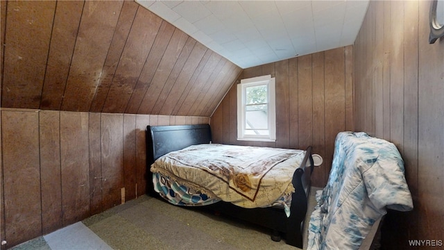 carpeted bedroom with lofted ceiling and wood walls