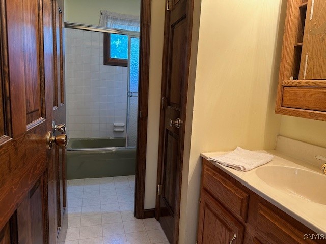 bathroom featuring enclosed tub / shower combo, vanity, and tile patterned floors