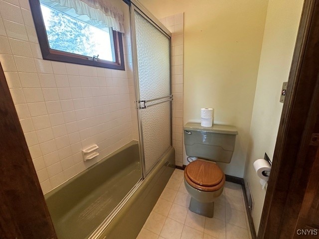 bathroom with bath / shower combo with glass door and toilet