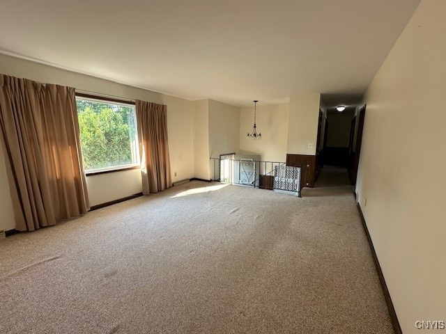 unfurnished living room with an inviting chandelier and carpet floors