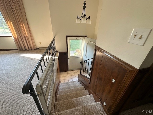 staircase featuring a chandelier and carpet