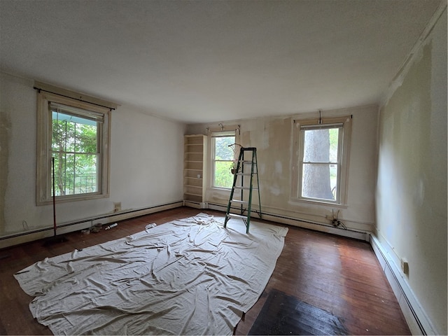 unfurnished room featuring dark hardwood / wood-style flooring, a baseboard heating unit, and plenty of natural light