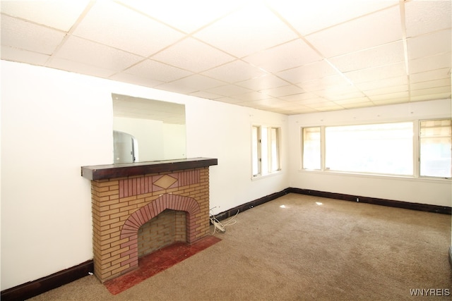 unfurnished living room with carpet floors, a drop ceiling, and a fireplace