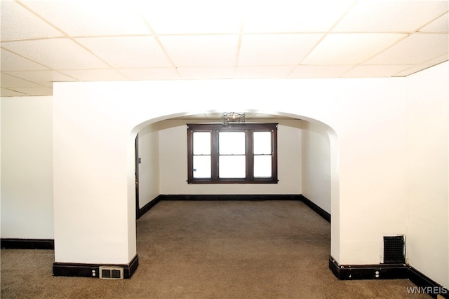 carpeted spare room featuring a drop ceiling