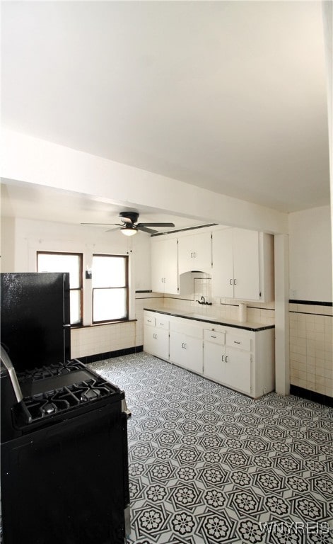 interior space featuring black appliances, ceiling fan, and white cabinetry