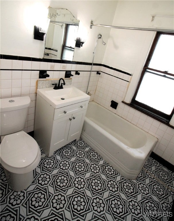 full bathroom featuring vanity, toilet, bathing tub / shower combination, tile walls, and tile patterned flooring