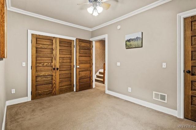 unfurnished bedroom featuring ornamental molding, ceiling fan, and light colored carpet