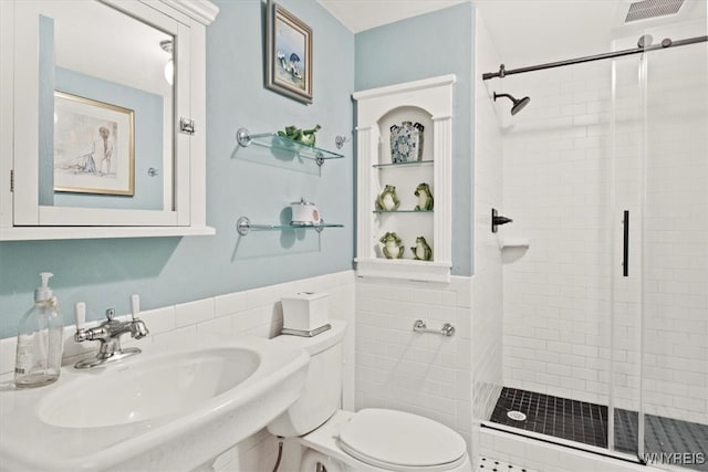 bathroom featuring sink, a shower with shower door, and toilet